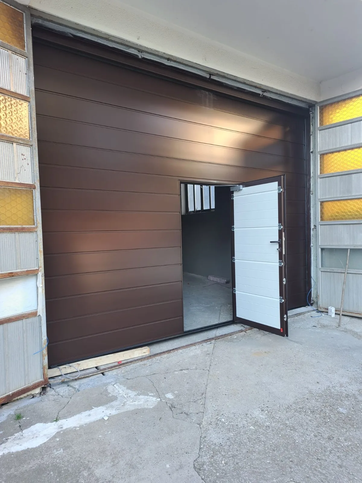 Brown sectional door with an integrated pedestrian door in an existing opening