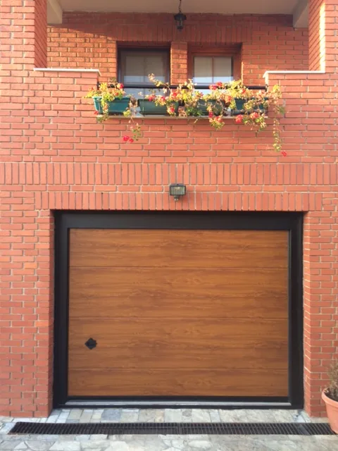 Wood-effect sectional garage door on a brick facade