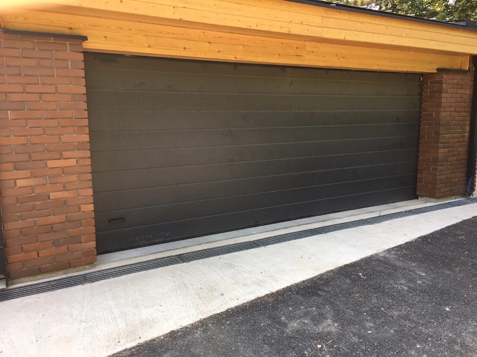 Dark sectional garage door between brick pillars